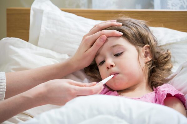 Mother measuring temperature of her ill child